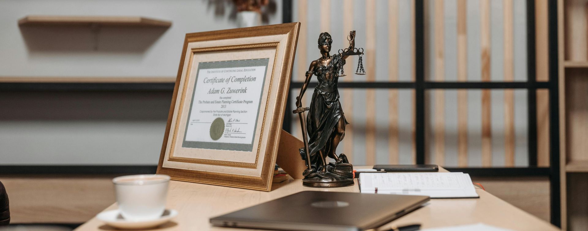 A professional handshake in an office with diploma and Lady Justice statue, symbolizing law and achievement.